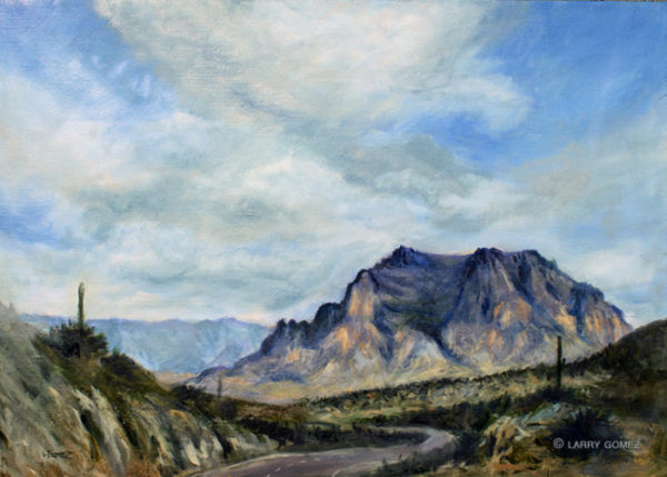 purple mountain with winding highway in foreground and blue mountains in the background